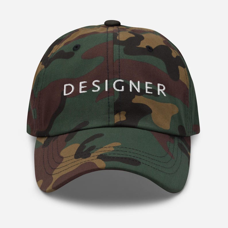 May include: Camouflage baseball cap with the word "DESIGNER" embroidered in white on the front.