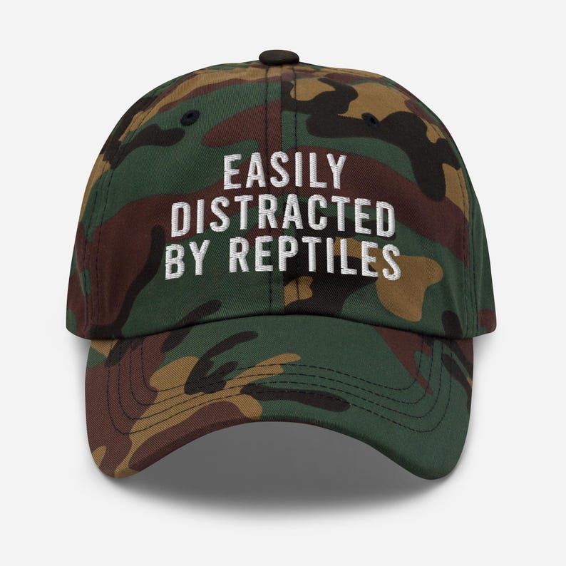 May include: A camouflage baseball cap with the text "EASILY DISTRACTED BY REPTILES" embroidered in white.