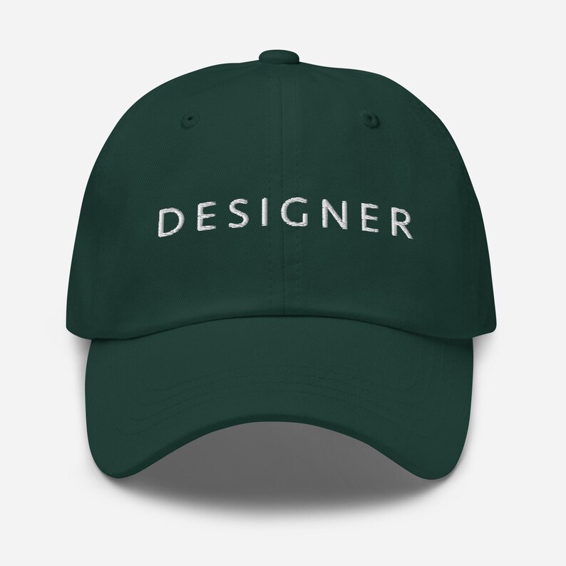 May include: A dark green baseball cap with the word "DESIGNER" embroidered in white on the front.