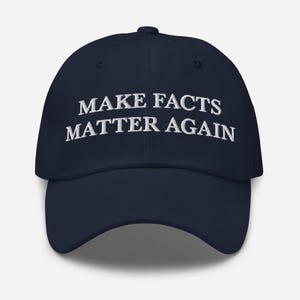 May include: A navy blue baseball cap with white embroidered text that reads "MAKE FACTS MATTER AGAIN".