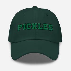 Op de afbeelding: Een donkergroene baseballcap met het woord "PICKLES" in groene blokletters geborduurd. De cap heeft een gebogen klep en een verstelbare band. Een klassiek, casual accessoire.