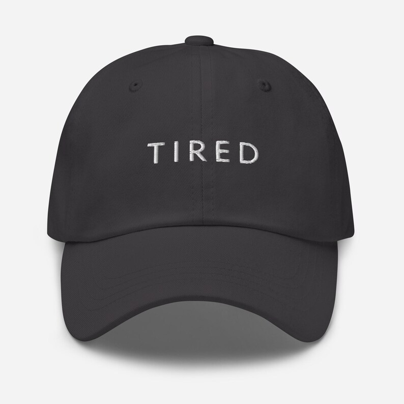 May include: A dark gray baseball cap with the word "TIRED" embroidered in white on the front.