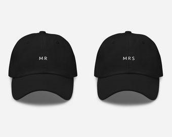 May include: Two black baseball caps with white embroidered text. The cap on the left says "MR" and the cap on the right says "MRS".