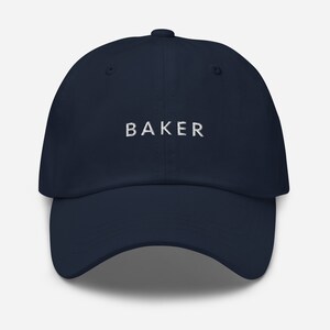 May include: A navy blue baseball cap with white embroidered text that reads "BAKER".