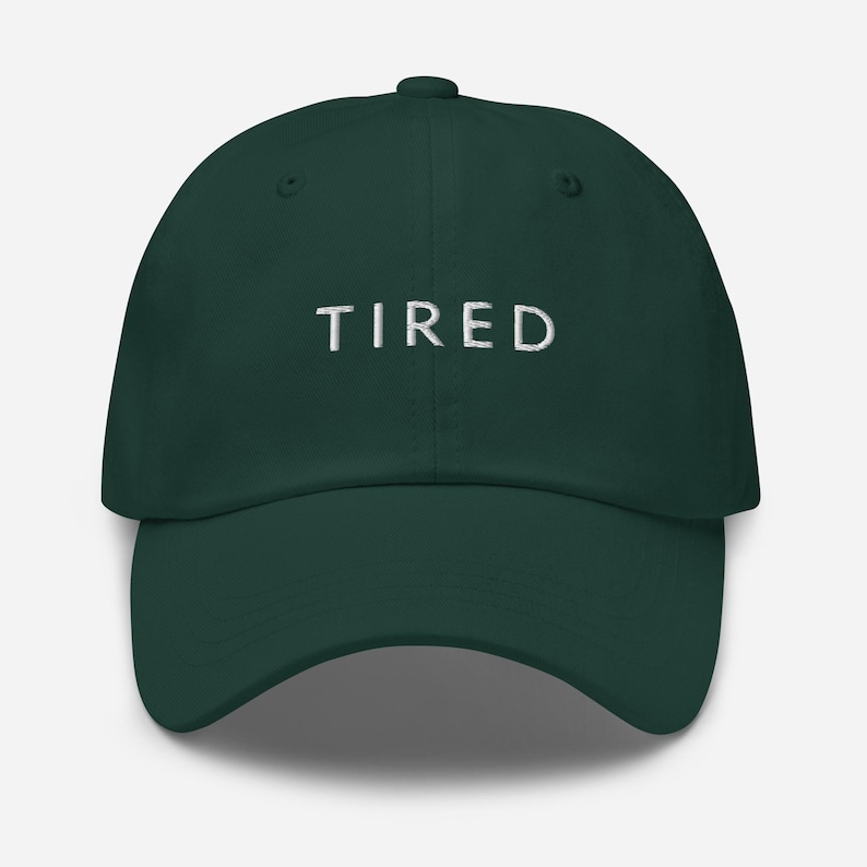 May include: A dark green baseball cap with the word "TIRED" embroidered in white on the front.