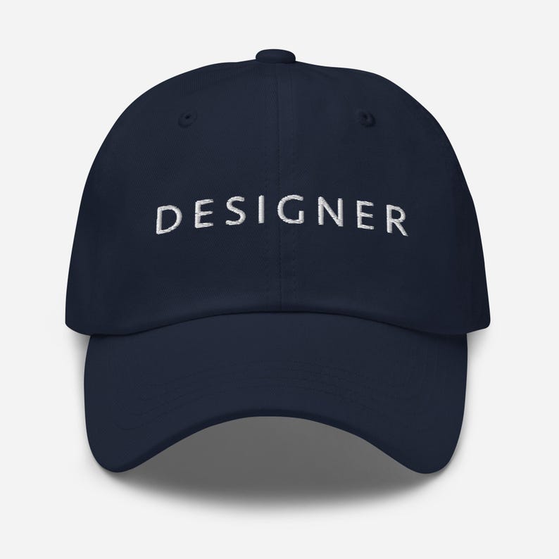 May include: A navy blue baseball cap with the word "DESIGNER" embroidered in white on the front.