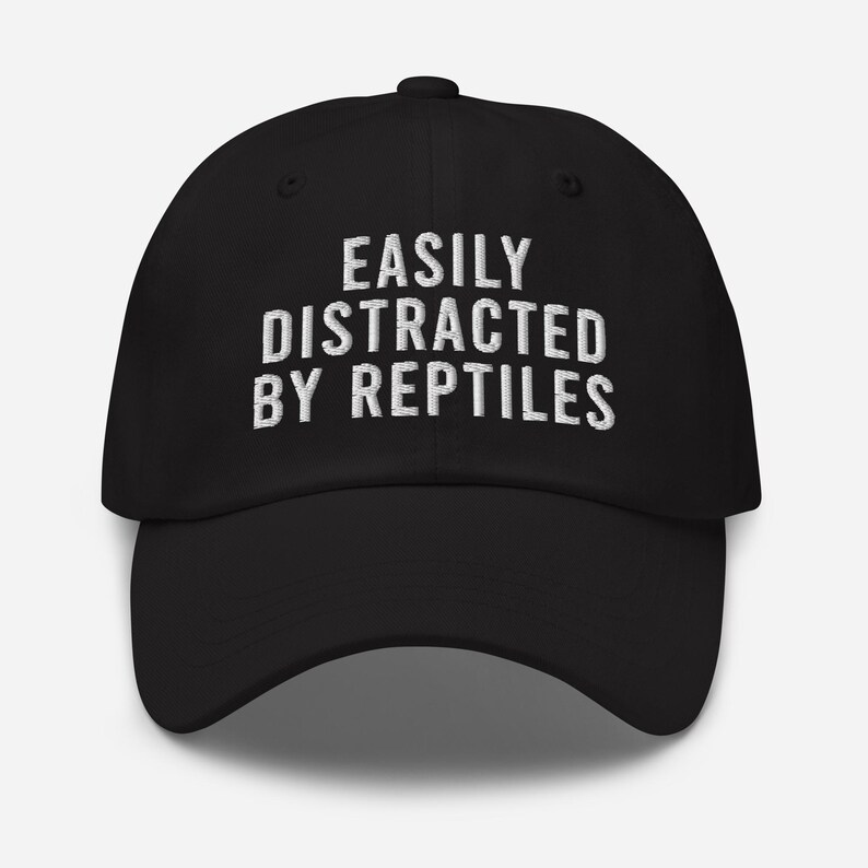 May include: Black baseball cap with white embroidered text that reads "Easily Distracted By Reptiles".