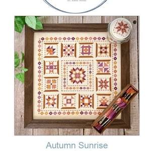May include: A cross stitch pattern titled "Autumn Sunrise" by Count Your Stitches Designs. The pattern features a variety of colorful quilt blocks in shades of orange, pink, and brown.