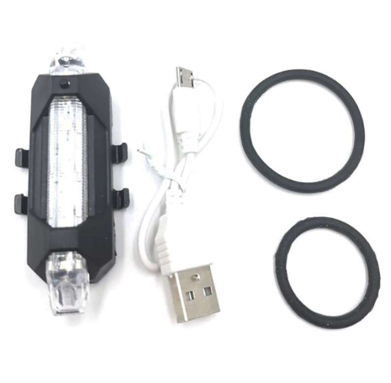 May include: A black bicycle light with a white LED light strip and two clear LED lights. Includes a USB charging cable and two black rubber rings for mounting. The light is designed for bicycle safety.