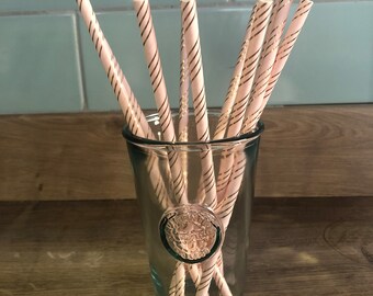 May include: A glass with pink and gold striped paper straws. The glass has a decorative design on the front.