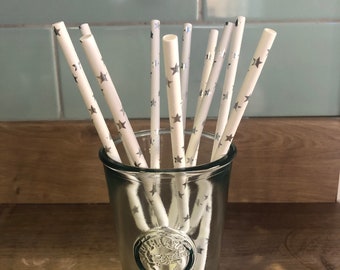 May include: A glass jar filled with white paper straws with silver star designs. The straws are arranged vertically in the jar.