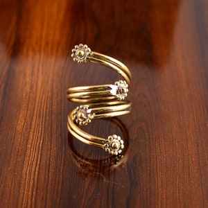 May include: A gold-toned spiral ring with four decorative flower-shaped accents.
