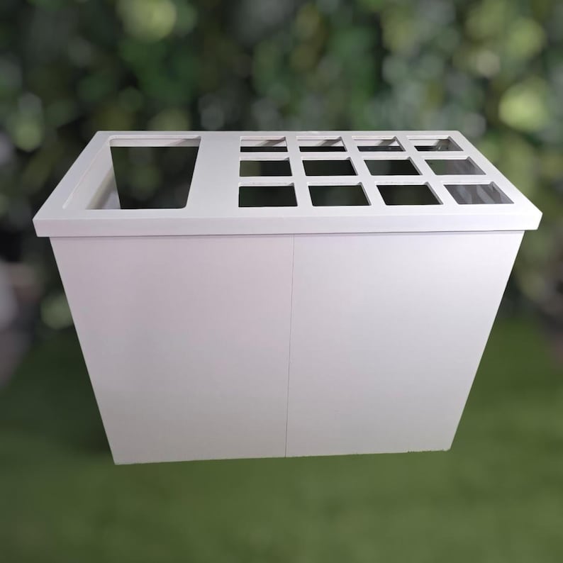 May include: A white, rectangular planter box with a sloped design. The top features a large square opening on the left and a grid of smaller square openings on the right. The box is made of a solid, opaque material.