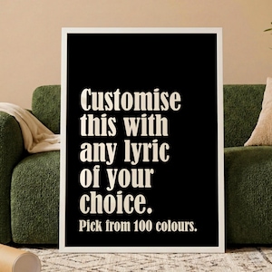 May include: A framed black print with white text that reads "Customise this with any lyric of your choice. Pick from 100 colours." The print is displayed against a green sofa.