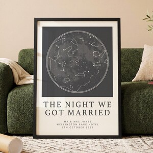 May include: A framed print with a celestial map design, showing constellations in a circular arrangement against a dark backdrop. The text "THE NIGHT WE GOT MARRIED" is displayed below, along with names, location, and date. The print is in a black frame.
