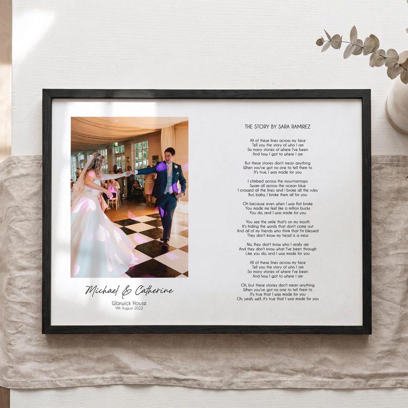 May include: A framed wedding print with a photo of a couple dancing, inscribed with "Michael & Catherine" and the date "9th August 2022." The right side features song lyrics titled "THE STORY BY SARA RAMIREZ."