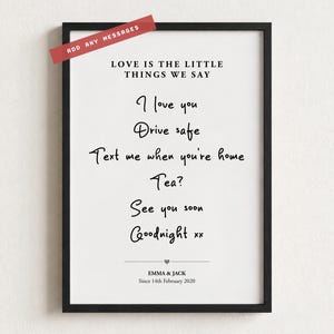 May include: A black framed wall art print featuring the text LOVE IS THE LITTLE THINGS WE SAY followed by handwritten-style phrases including I love you, Drive safe, Text me when you're home, Tea?, See you soon, Goodnight xx, and names EMMA & JACK.
