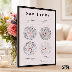 May include: A framed white poster titled OUR STORY featuring four circular black and white street maps, each marked with a small red heart. The text includes dates and locations for first date, engagement, first born, and wedding events.
