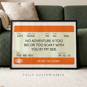May include: A framed print designed to look like a train ticket. The orange and white design features the text "NO ADVENTURE IS TOO BIG OR TOO SCARY WITH YOU BY MY SIDE." The print also includes the text "THEE AND MEEE" and "WE ARE THE LUCKIEST."