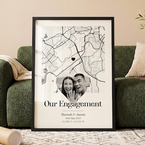 May include: Framed print featuring a black and white map with a heart marking a location. A heart-shaped photo of a smiling couple is centered below the map. The text "Our Engagement" is displayed, along with names and a date.