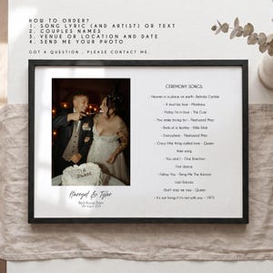 May include: A framed wedding print with a photograph of a couple and their ceremony song lyrics. The black frame encloses a white background with the couple's names, wedding date, and venue. The print also includes a list of songs and ordering instructions.