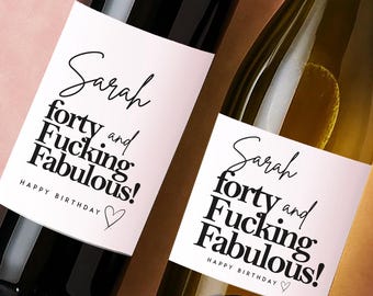 May include: Two glass bottles with white rectangular labels featuring black text that reads Sarah forty and Fucking Fabulous! HAPPY BIRTHDAY with a small heart outline. One bottle is dark glass and the other is clear glass with a gold foil neck.