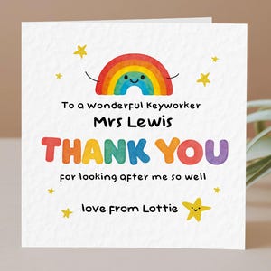 May include: A white card with a rainbow and stars design. Text reads: "To a wonderful Keyworker Mrs Lewis THANK YOU for looking after me so well love from Lottie."