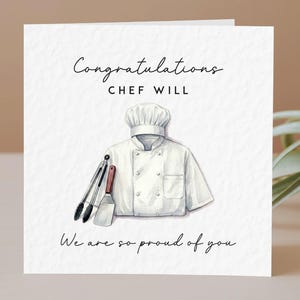 May include: A square greeting card with a white textured background featuring a watercolour illustration of a white chef coat, a toque, and metal kitchen tongs and a spatula. The text reads: Congratulations CHEF WILL We are so proud of you.