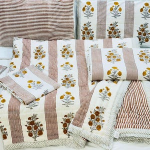 Pode incluir: Um conjunto de roupa de cama listrada branca e marrom com um padrão floral. O conjunto inclui um edredom, duas fronhas e duas almofadas menores.