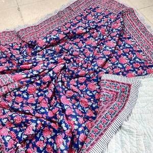 Può includere: Una trapunta in cotone con motivo floreale blu e rosa con un bordo bianco. La trapunta è perfetta per aggiungere un tocco di colore e stile a qualsiasi camera da letto.