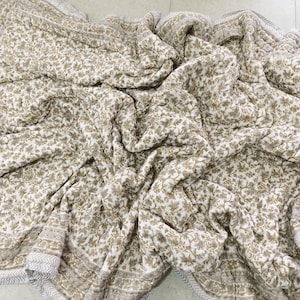 Könnte beinhalten: Eine weiße und braune Steppdecke mit floralem Muster und einem grauen und weißen Rand. Die Steppdecke ist aus Baumwolle und weich und bequem.