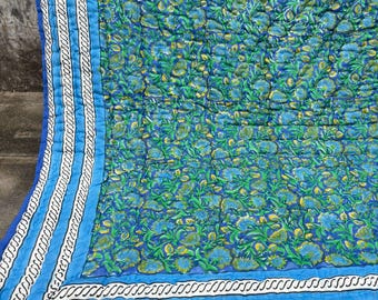Könnte beinhalten: Eine gesteppte Decke mit einem dichten Blumenmuster in Blau-, Grün- und Gelbtönen. Der Rand besteht aus einem breiten hellblauen Band, einem dünnen weißen Streifen mit schwarzem seilartigem Design und einem dunkelblauen Abschluss.