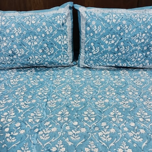 Könnte beinhalten: Ein blaues und weißes Bettwäsche-Set mit Blumenmuster und zwei passenden Kissenbezügen. Die Bettwäsche hat ein traditionelles indisches Design.