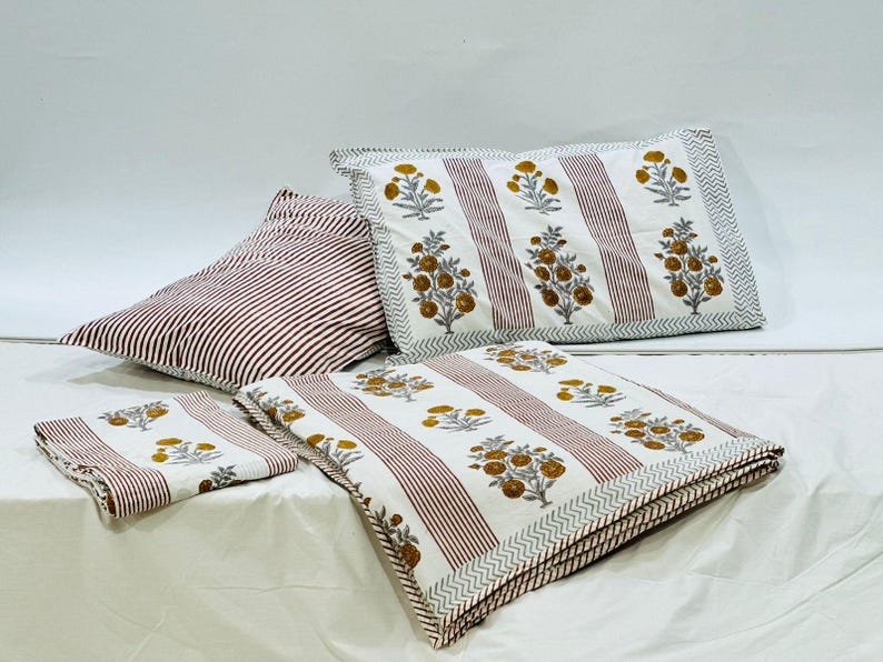May include: A white and red striped bedding set with a floral pattern in shades of yellow and blue. The set includes a duvet cover, two pillowcases, and a throw pillow.
