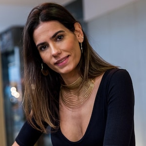 Peut inclure: Une femme aux longs cheveux bruns portant un haut noir à col en V et un collier ras du cou en or à plusieurs rangs.