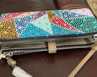 May include: A multi-colored leather wallet with a unique dot pattern design. The wallet has two zippered compartments and a beige strap.