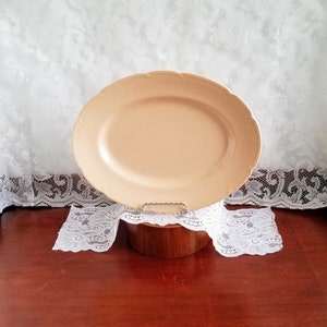 Peut inclure: Un plat de service ovale en céramique de couleur pêche pâle avec un bord festonné.