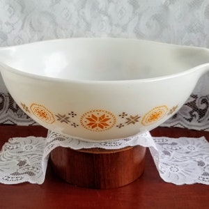 May include: White ceramic mixing bowl with a brown and orange geometric pattern. The bowl has two pouring spouts on the sides.