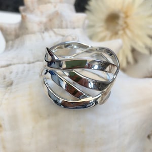 Könnte beinhalten: Ein silberner Ring mit einem geflochtenen Design. Der Ring ist dick und hat eine breite Band.