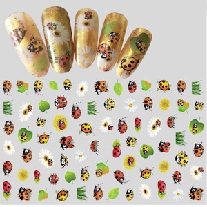 May include: A sheet of nail art stickers featuring a repeating pattern of ladybugs, flowers, and leaves. The ladybugs are red with black spots and yellow accents. The flowers are white with yellow centers. The leaves are green.