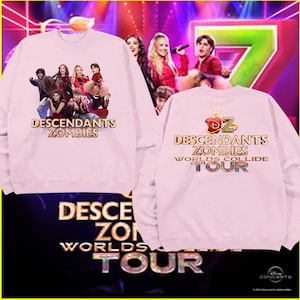 May include: Light pink sweatshirt featuring a graphic of the cast of Descendants Zombies. The front of the sweatshirt has the words "Descendants Zombies" in gold lettering. The back of the sweatshirt has the words "Descendants Zombies Worlds Collide Tour".