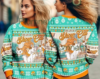 May include: A teal long-sleeve sweatshirt with an orange collar and cuffs, featuring a repeating holiday-style pattern and a central graphic of a white cat with a large orange tail. The text reads The Life of a Show Cat.