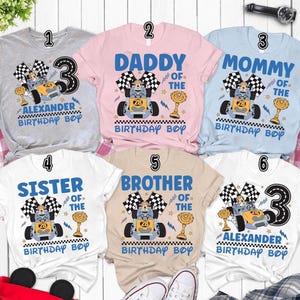 May include: A collection of six short-sleeved t-shirts with racing-themed designs. Each shirt features a cartoon race car, checkered flags, and text such as "Daddy", "Mommy", "Brother", "Sister", and "Birthday Boy". The shirts are in various colors.
