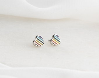 May include: A pair of silver heart-shaped earrings with a rainbow stripe design.
