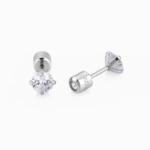 May include: Two silver stud earrings with clear, round, faceted gemstones. One earring is upright, displaying the gemstone and post. The other earring is lying on its side, showing the post and the back of the gemstone.