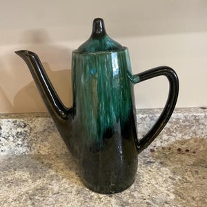 May include: A green and black ceramic teapot with a lid. The teapot has a unique glaze pattern with streaks of green and black.
