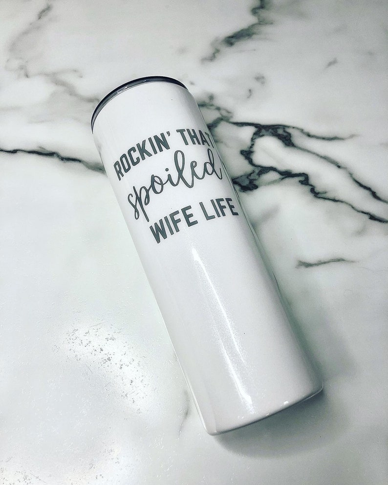May include: White stainless steel tumbler with a silver inscription that reads "Rockin' That Spoiled Wife Life".