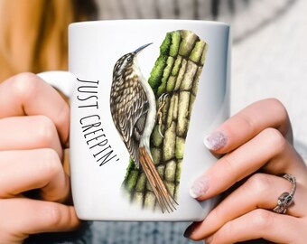 Puede incluir: Taza de cerámica blanca con una ilustración de un pájaro marrón y blanco en un tronco de árbol verde y marrón. El texto "JUST CREEPIN'" está impreso en la taza.