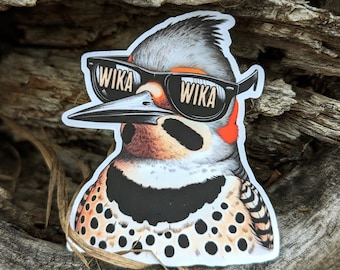 May include: A sticker of a cartoon woodpecker wearing sunglasses with the word "WIKA" on each lens. The woodpecker has a black and white spotted pattern on its chest and a red stripe on its head.