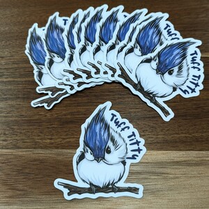 May include: A set of 10 bluebird stickers with the text "Tuff Titty" on each sticker. The stickers feature a cartoon bluebird with a blue head and white body.